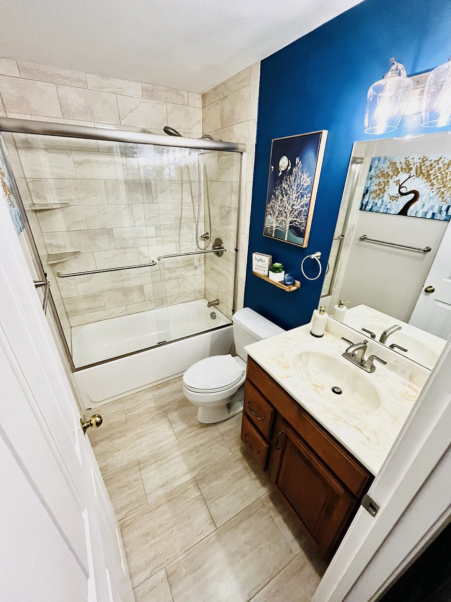 Updated second full bathroom with a tiled tub and shower, glass enclosure, generous vanity storage, and bright contemporary finishes.