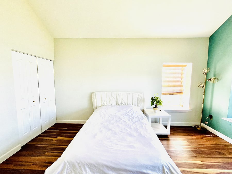 Bright, generously sized second bedroom with a comfortable bed, ample in-wall closet and under-bed storage space, and polished luxury flooring.