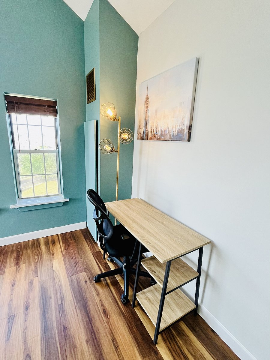 Dedicated workspace with an ergonomic chair, built-in shelving, warm lighting, and natural light for comfortable remote work.