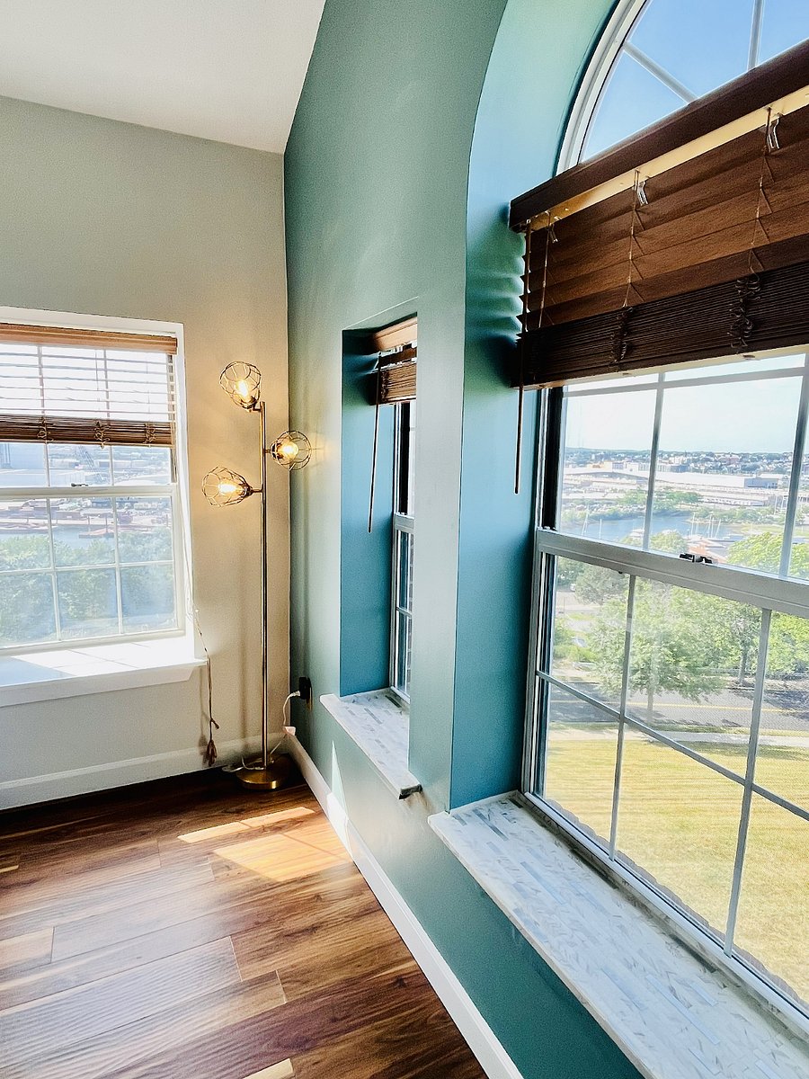 Oversized windows, including a distinctive arched window, fill the bedroom with sunlight and showcase elevated neighborhood and waterfront views.