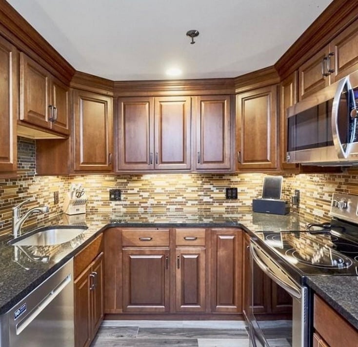 Well-equipped U-shaped kitchen with granite countertops, abundant cabinetry, tiled backsplash, recessed lighting, and stainless steel appliances.