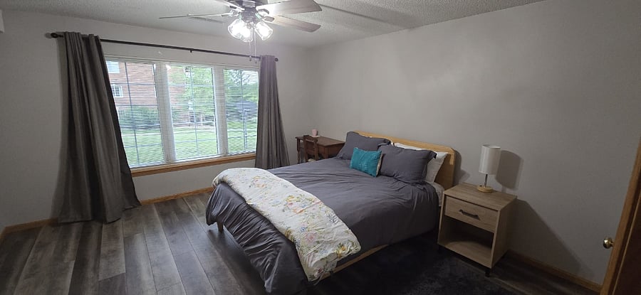 Bedroom with full dresser, nightstand, lamp, desk/chair, and blackout curtains