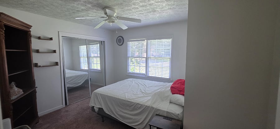 Bedroom 1, optional clock, large bookshelf for storage, 3 small shelves, Sliding mirror door with closet storage with hangers, queen bed with sheets, small night stand with charger access