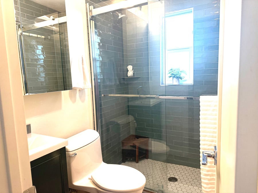 Updated tile shower with glass shower door & newer vanity