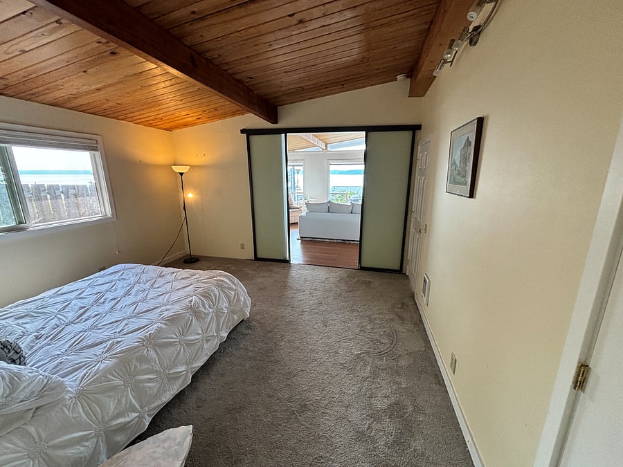 Master bedroom, with view out sliding doors to mountains and Puget Sound. Blinds on window.  35 inch TV in room. 