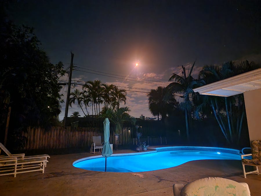 pool at night with rocket launch in sky