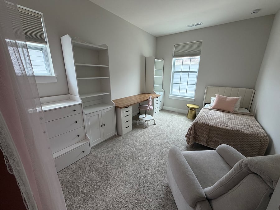 Kid's bedroom with attached closet, a large desk, generous bookshelves and a dresser as well as a recliner.