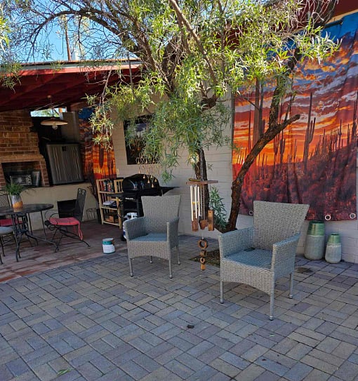 Sitting area in outdoor grill area. Large table and two additional sitting chairs.