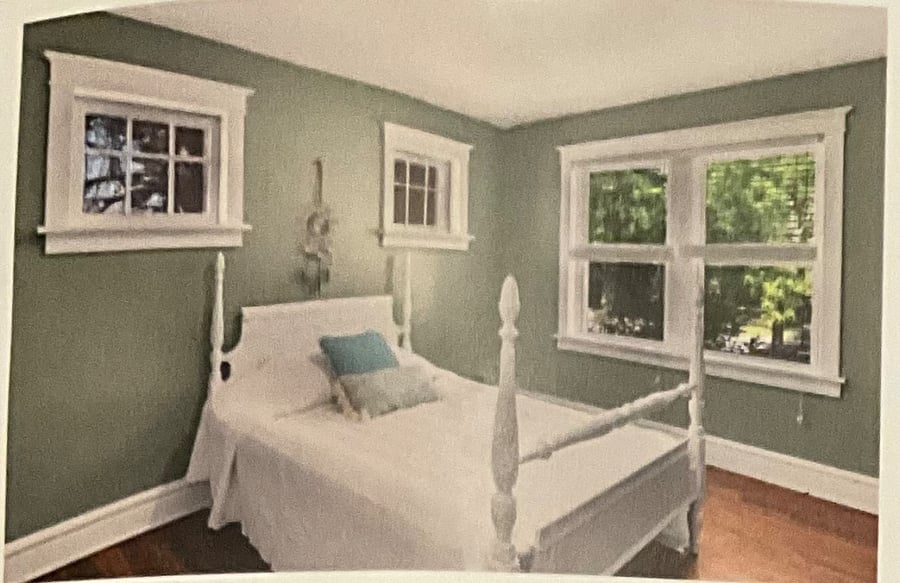 One of the two bedrooms on the main floor. New windows facing the front yard with lots of green space two small vintage windows above bed closet in bedroom.