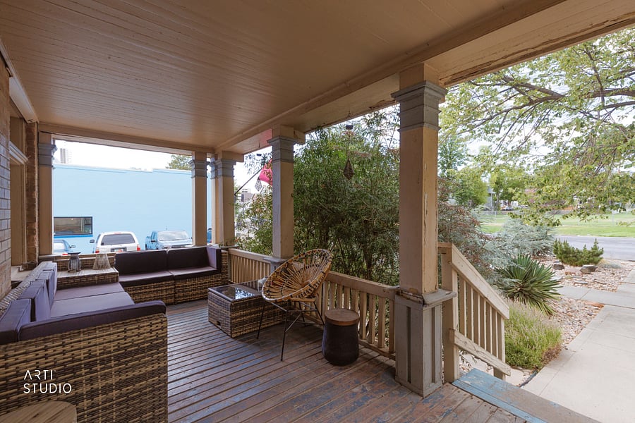 Off to the right, the porch has the character of a turn-of-the-century Southern porch, the kind you actually sit on for a while. L-shaped outdoor sofa seating for five plus a rattan chair, floating tables and a corner table for food or a drink, and solar lighting that glows at night.