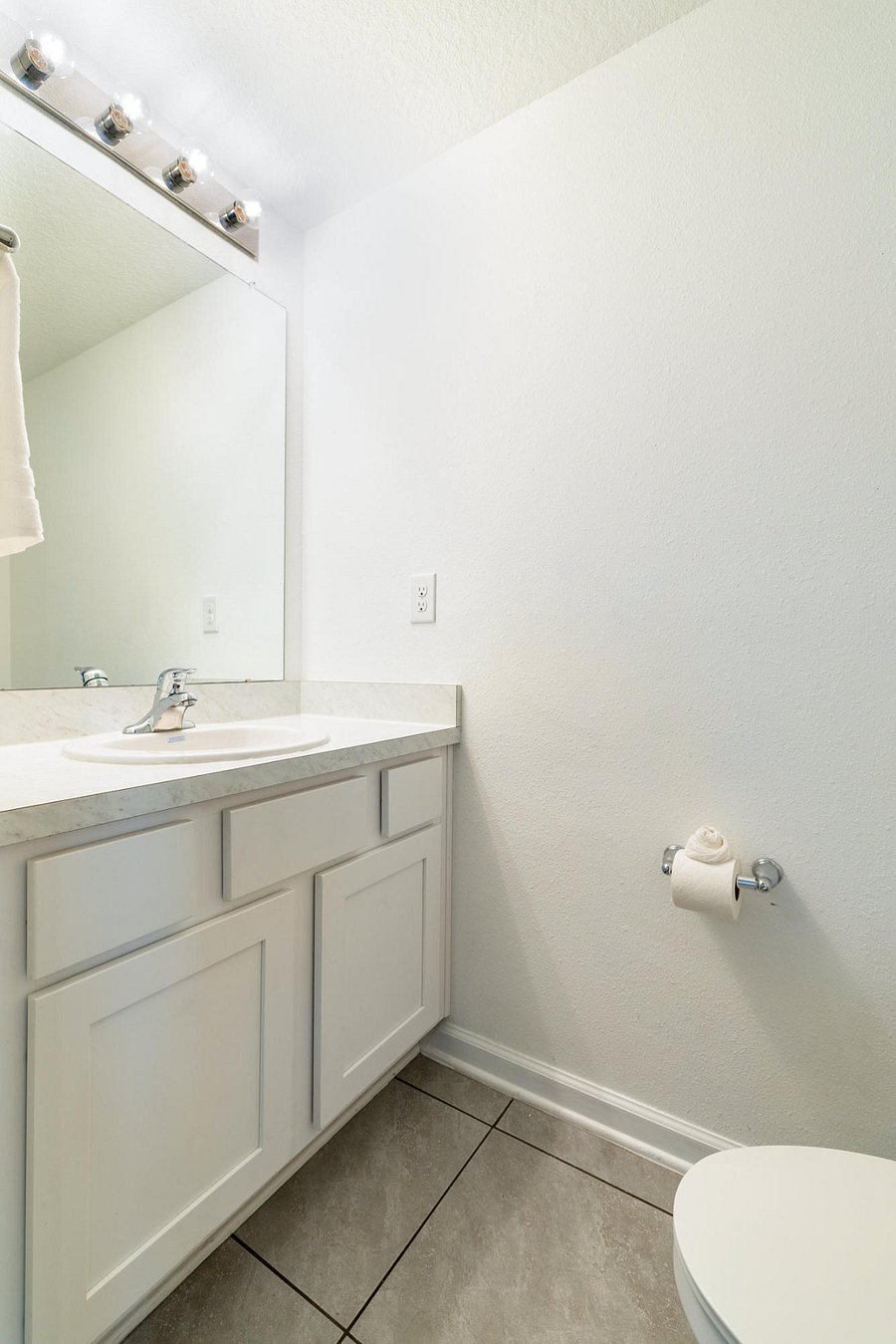 Downstairs half bath with vanity and bright mirror.