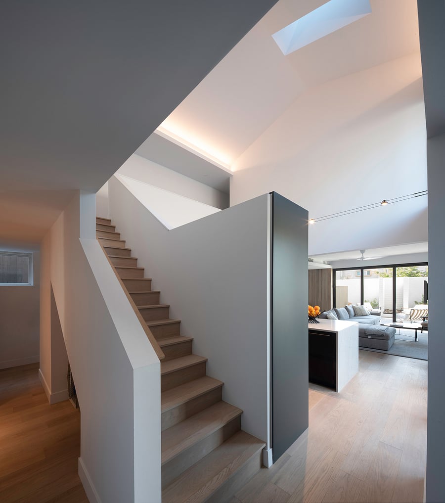 Entry / Stair / Natural Light: A light-filled arrival with clean lines, warm wood flooring, and architectural volume immediately sets the tone for the home.