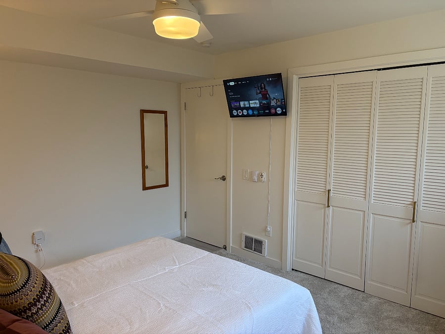 Another view of your private bedroom, featuring the mounted smart TV with Chromecast, a spacious closet, and a mirror conveniently located behind the door.