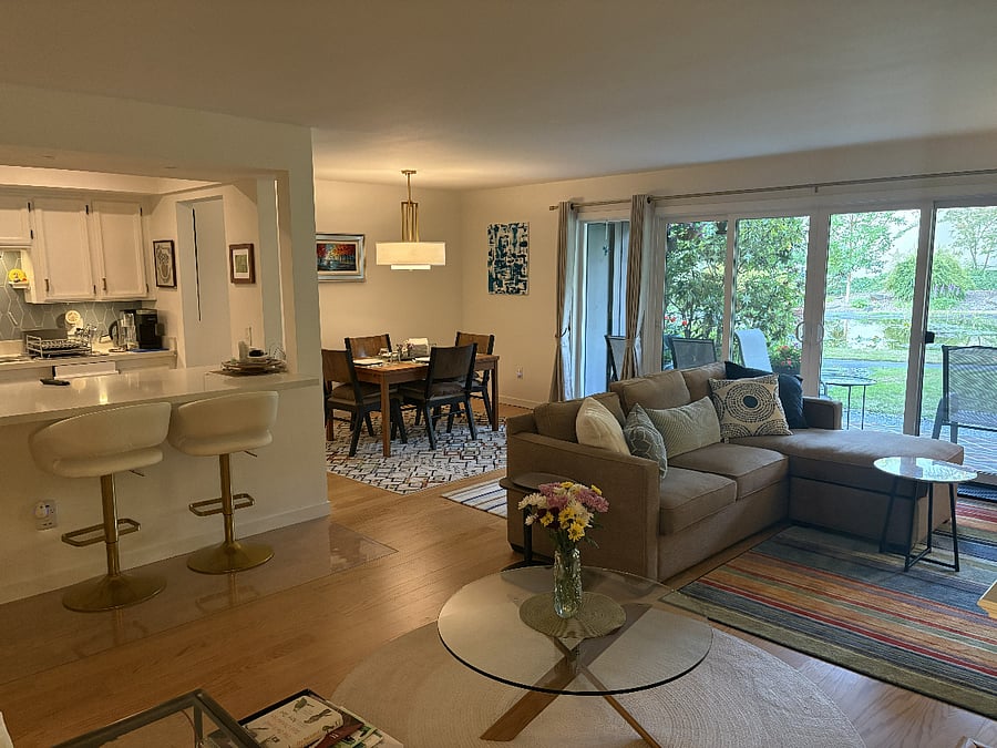 Relax in the shared living room, featuring comfortable seating, a 65-inch smart TV with Xfinity cable, and views of the landscaped grounds.