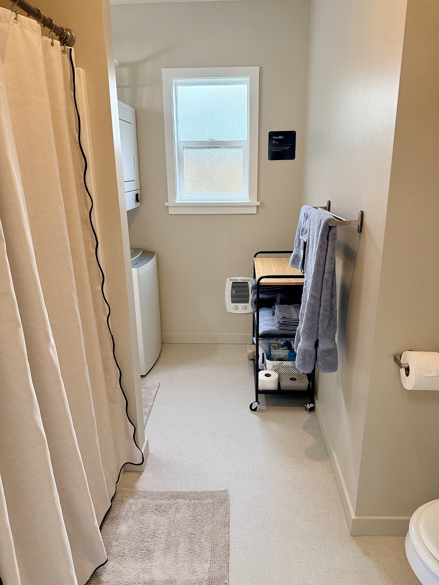 Spacious bathroom with walk-in shower, new washer/dryer, storage cart, and ample vanity storage.