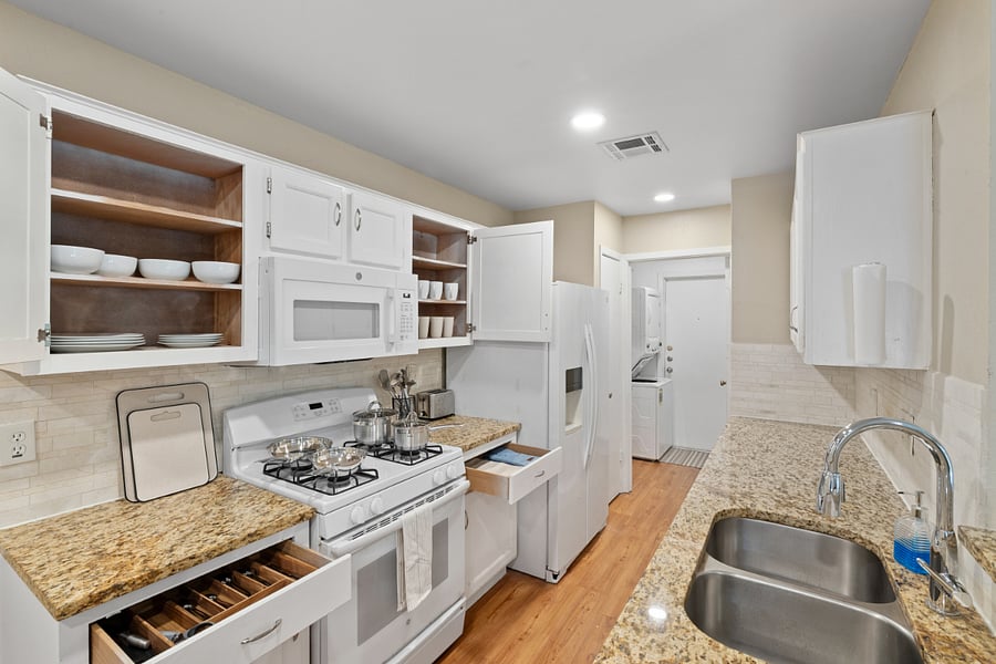 Kitchen equipped with cookware, dinnerware, silverware.