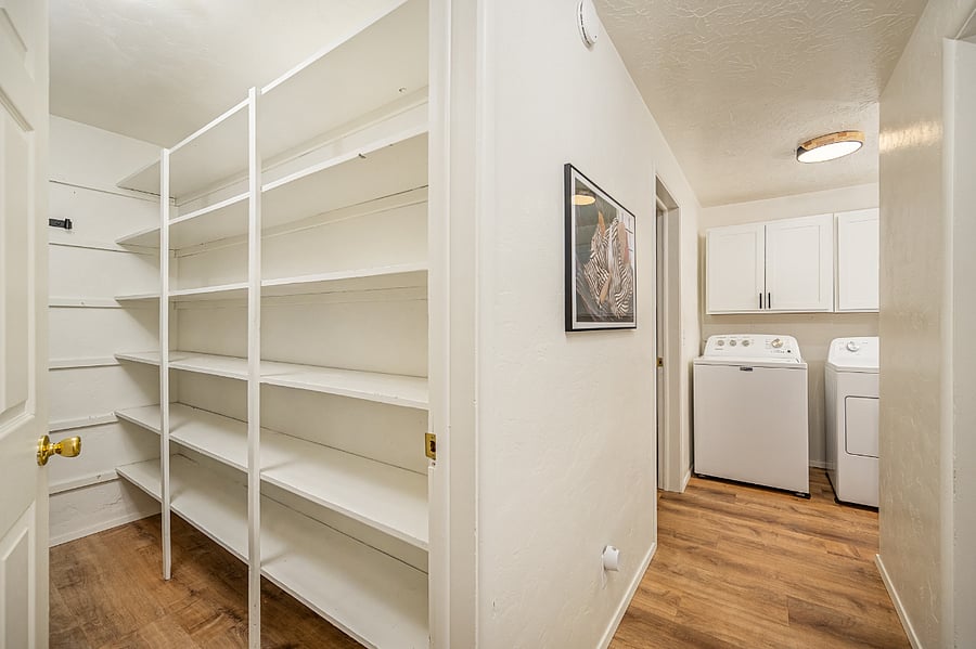 Separate pantry with door. Shelving is on both sides and there are hooks on the back wall.