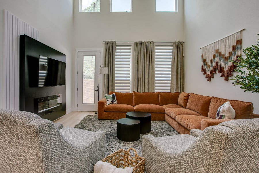 Sunny two story living room with plenty of seating and 65 inch Smart TV.