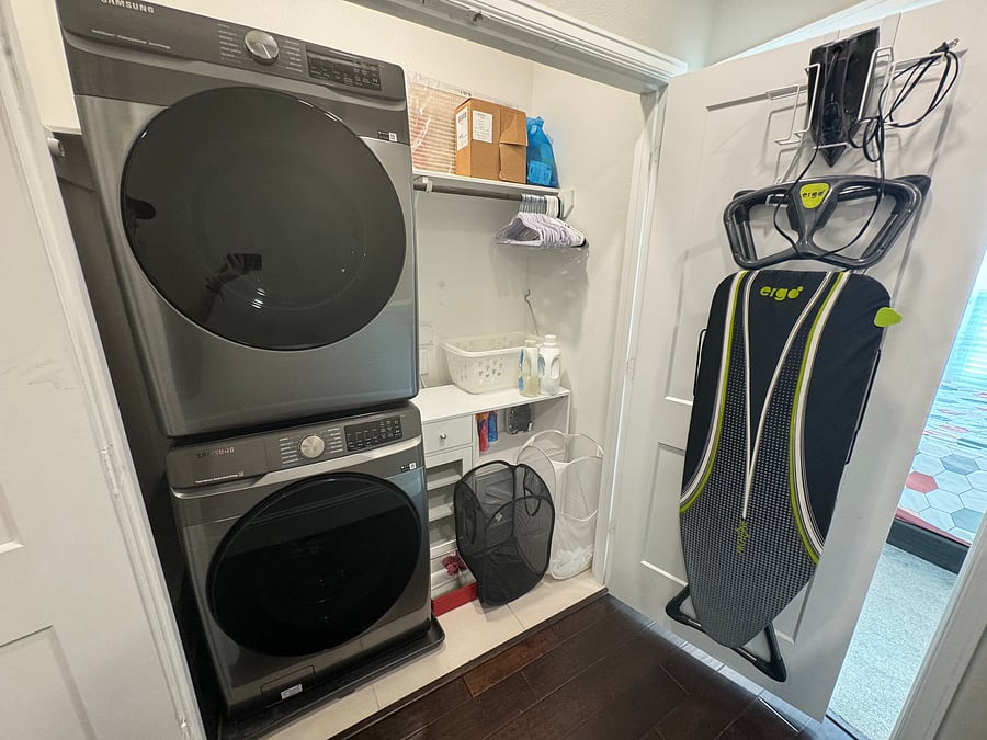 Laundry room with full sized separate washer and dryer, iron and ironing board, and laundry station