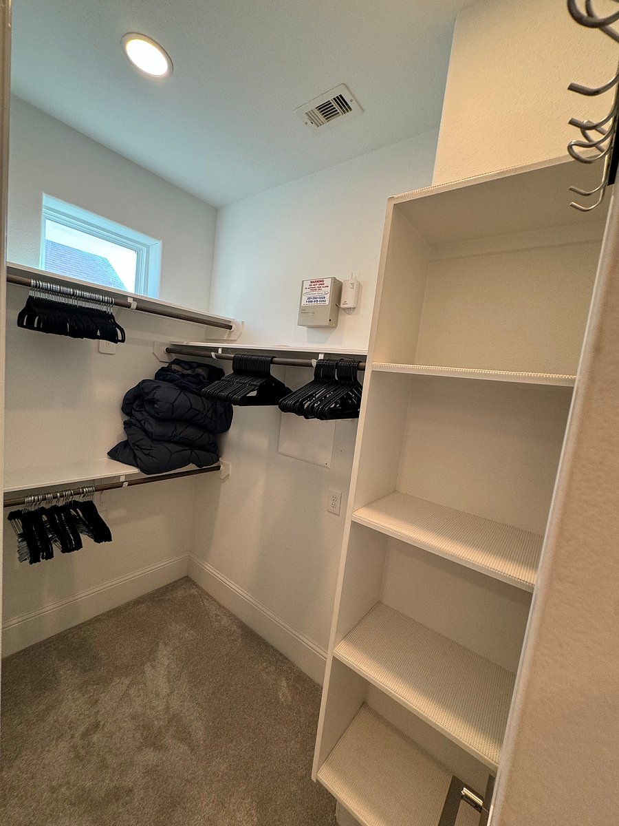 Master bedroom walk-in closet with hangers and storage shelves