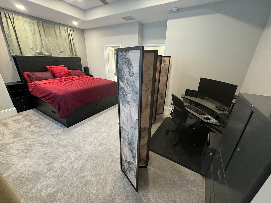 Master bedroom with dividing panels separating work station with sit/stand desk, large curved monitor, and office drawers & cabinets