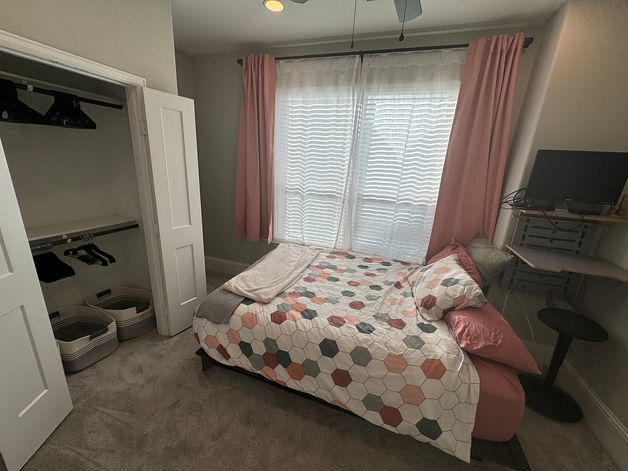 Upstairs bedroom with queen sized bed (with drawer), closet with hangers, and sit/stand workstation