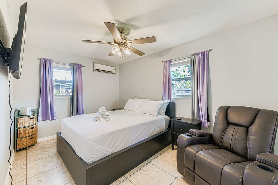 Secondary bedroom with queen bed, smart TV, and recliner.