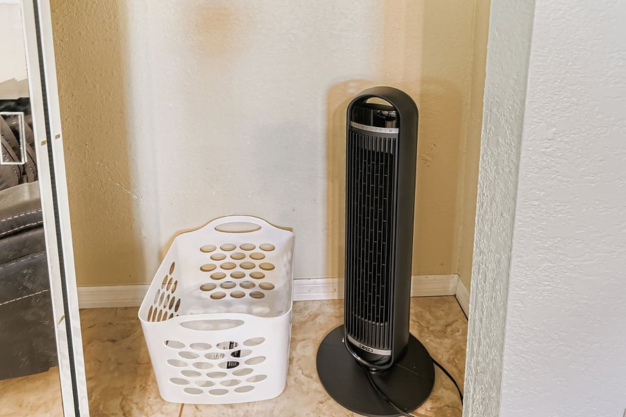 Secondary bedroom closet with laundry basket and portable fan.