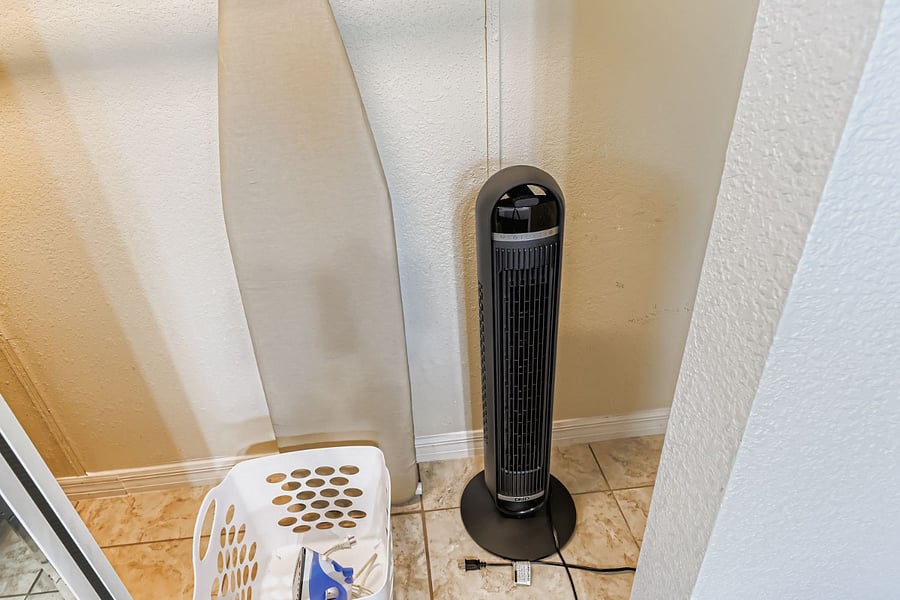 Master bedroom closet with Ironing board and iron, portable fan, and laundry basket.