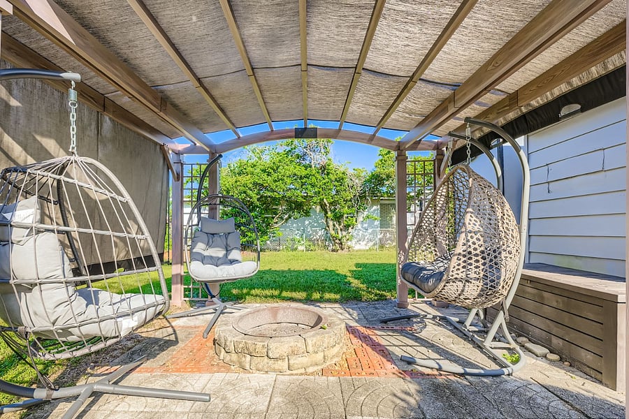 Covered pergola with hanging egg chairs and firepit. 