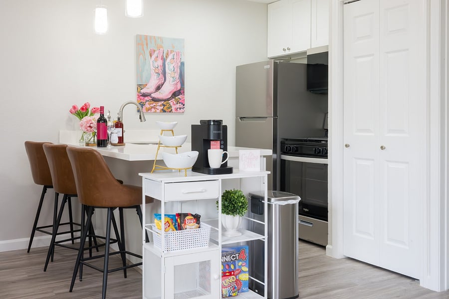 Modern kitchen features a sleek breakfast bar with stylish leather stools, a fully-equipped coffee station, and high-end stainless steel appliances.