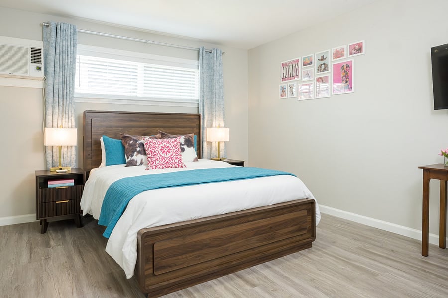 Unwind in a vibrant and restful bedroom featuring a rich wood bed frame, chic mid-century nightstands, and playful pops of color.