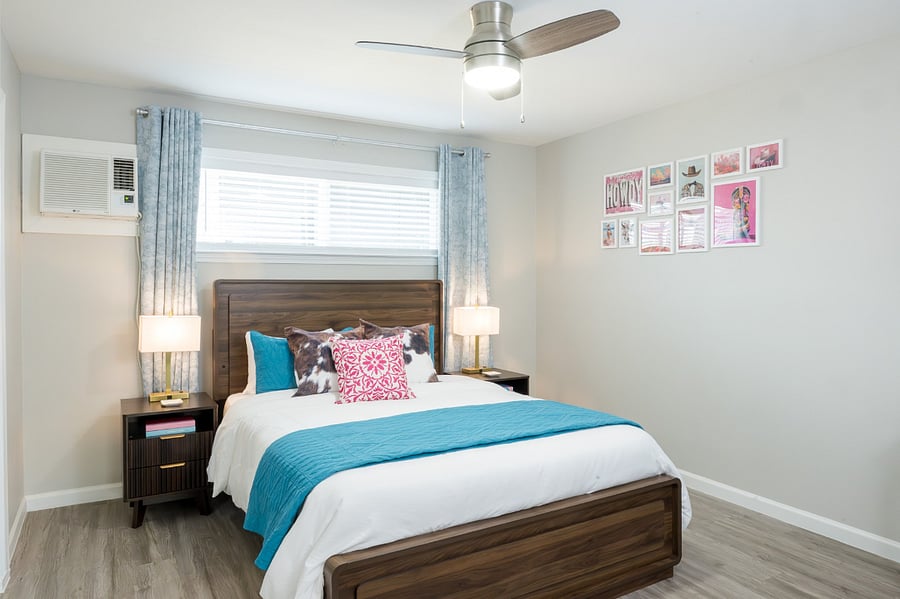 Cheerful bedroom with elegant gold-accented lamps meet a curated gallery wall.
