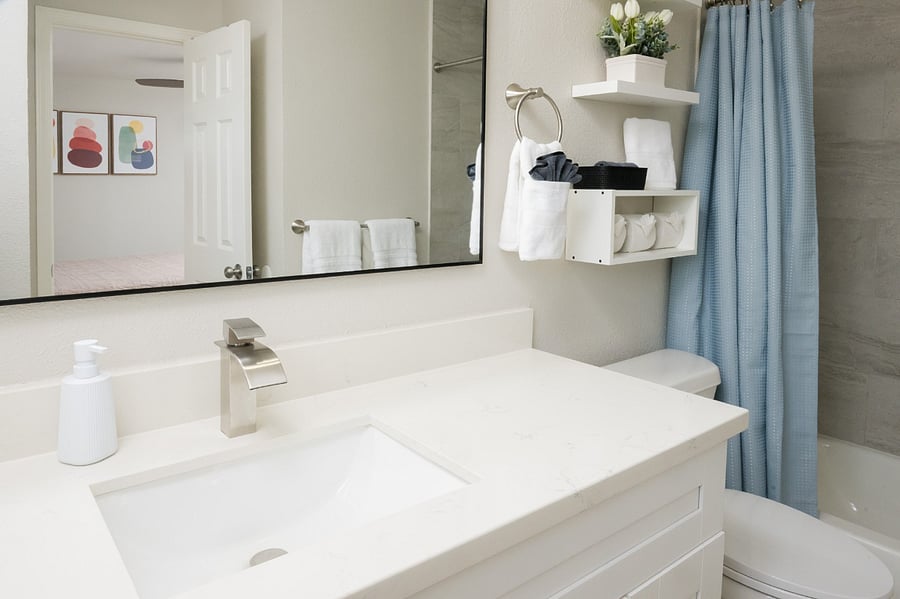 Contemporary bathroom features a clean white vanity with thoughtful storage shelving and a serene blue touches.