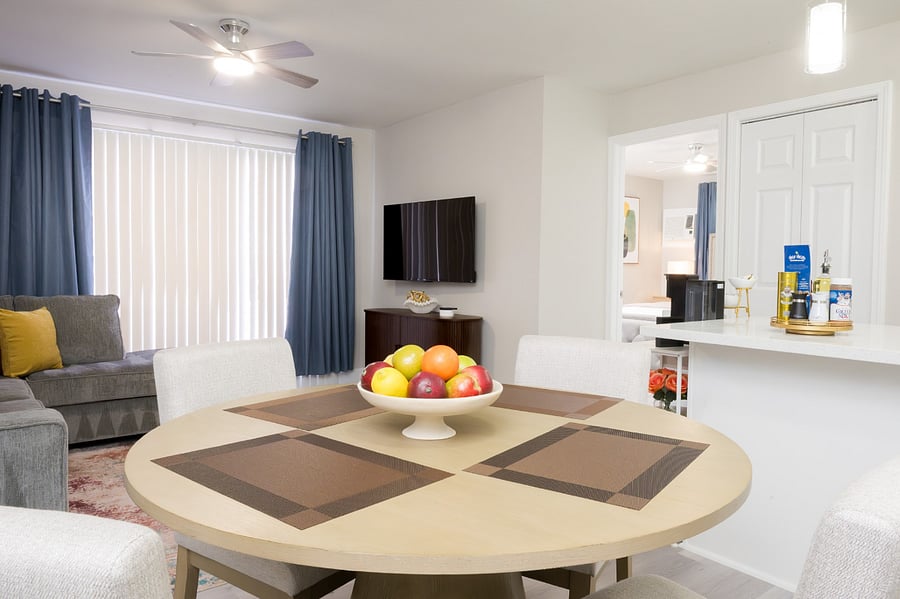 The dining area features elegant upholstered chairs and a modern round table, ideal for both dinner and remote work.