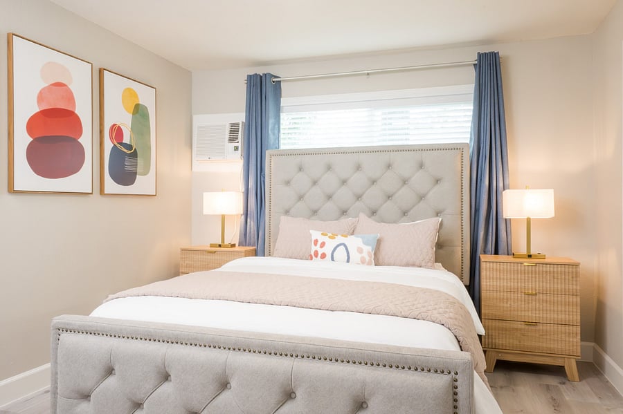 Relaxing master bedroom with a glamorous plush velvet button-tufted bed and decorative pillows.