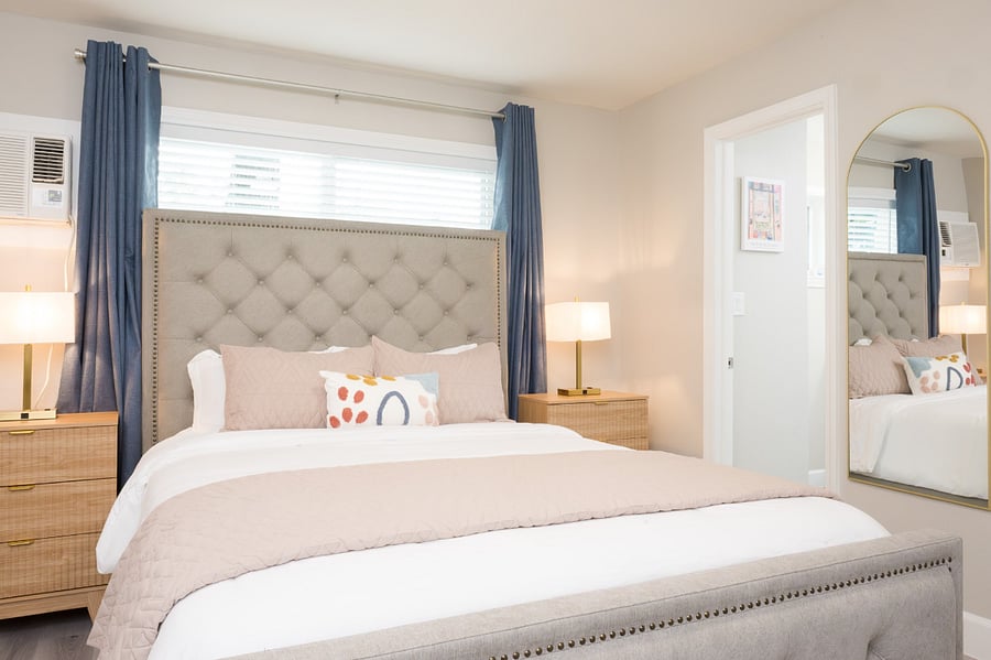 Serene master bedroom featuring a luxurious button-tufted bed, chic brass bedside lamps.
