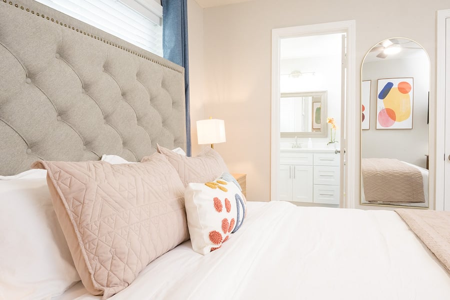 Bright bedroom showcasing a stylish mix of textures, from the velvet headboard to the artisan accent pillows.