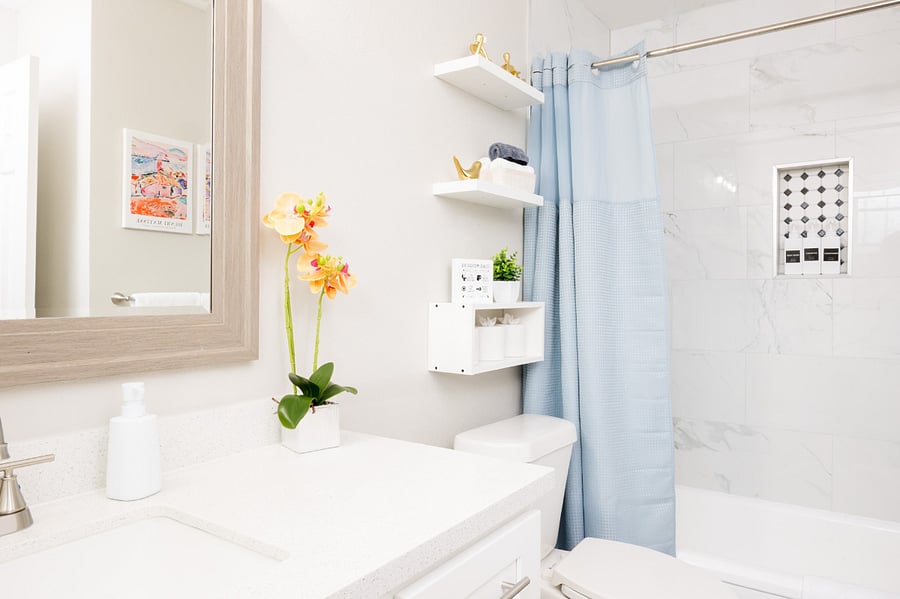 Modern vanity with a large wood-framed mirror and thoughtful floating shelves for extra storage.