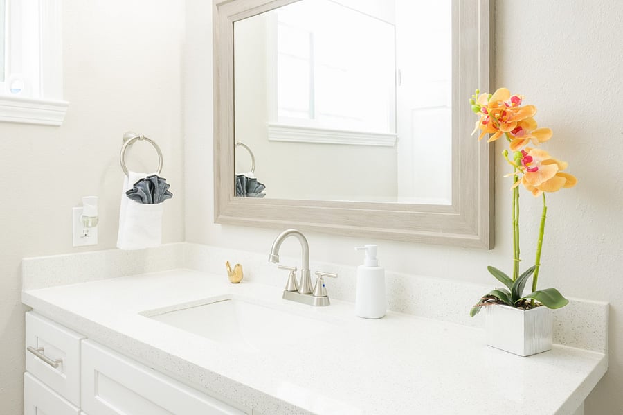 A light-filled vanity with clean lines, a full-length mirror, and guest amenities.