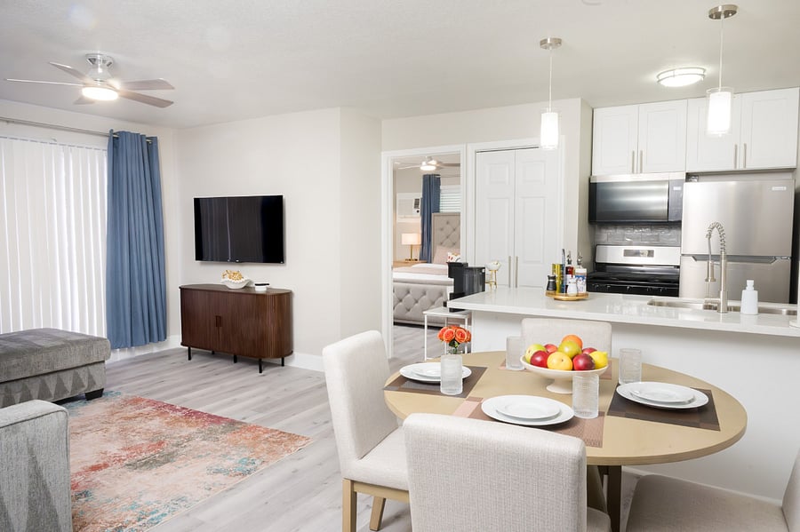 An elegant open-concept space featuring a modern round dining table with high-back upholstered chairs.