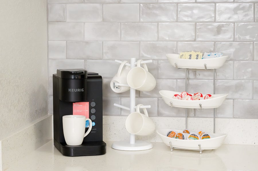 Start your mornings right at this sleek coffee station, fully equipped with a modern brewer and a thoughtful selection of pods.