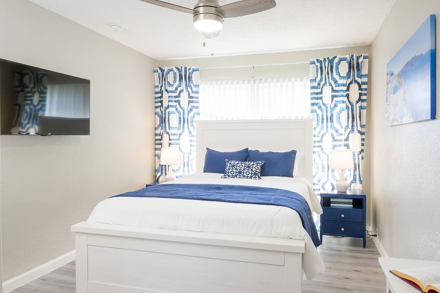 Modern bedroom with a cozy queen bed, elegant navy accents, a mounted flat-screen TV for entertainment.