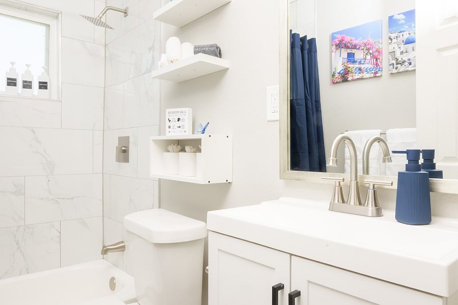 Bathroom with marble-style tiling, a modern rainfall showerhead, and thoughtful storage solutions.