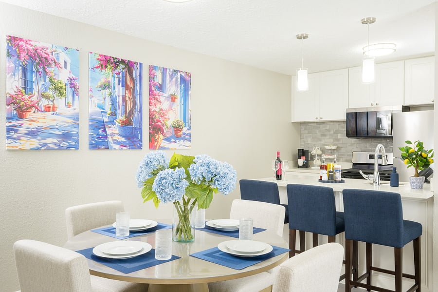 Beautifully coordinated living space, where vibrant floral artwork and deep blue accents create a lively atmosphere for dining.