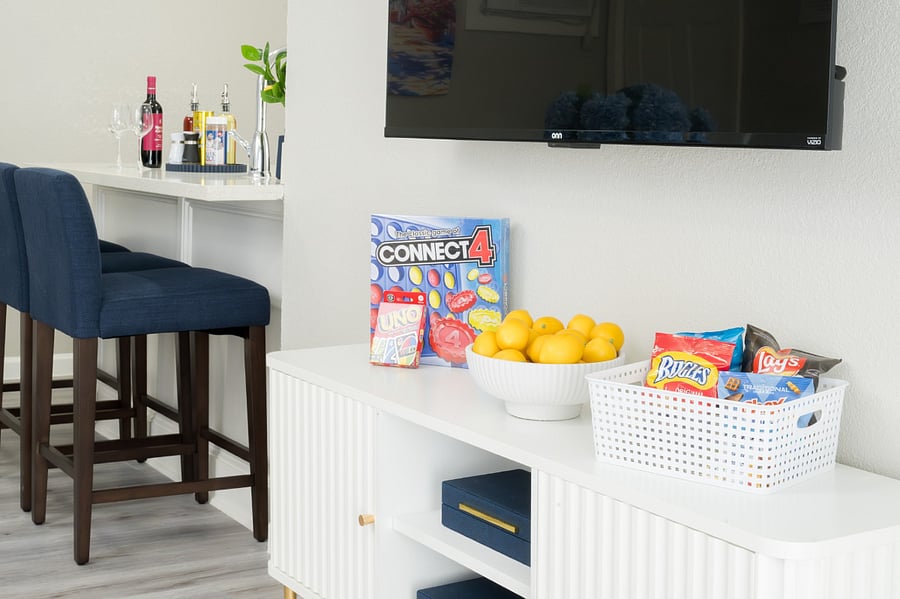 Experience a playful and inviting vibe with a modern media console stocked with games and snacks.