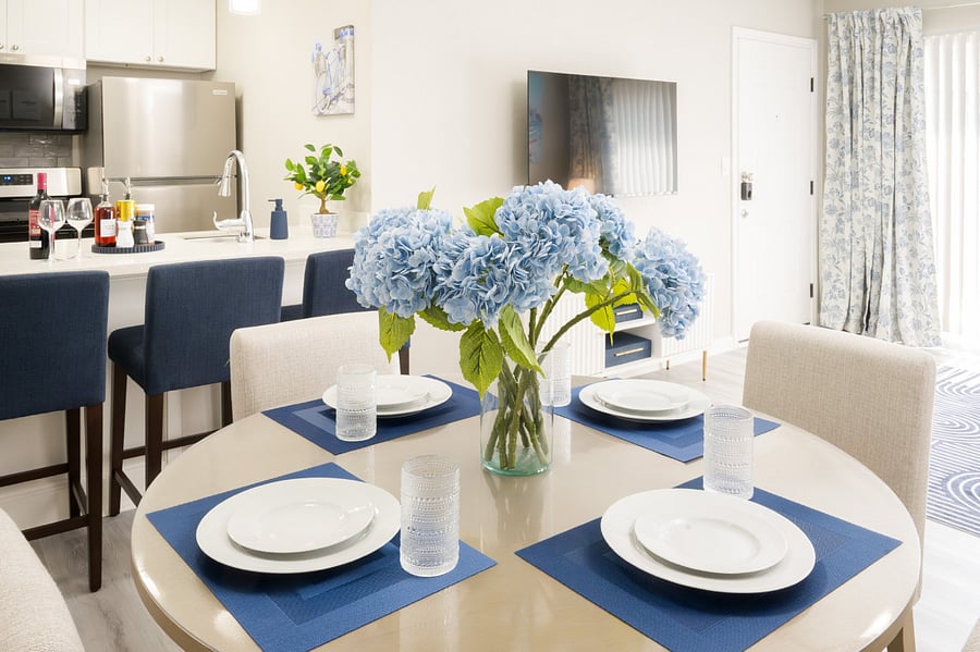 Elegant round dining table, beautifully set with coastal blue accents and fresh hydrangeas, offering a bright space for shared meals.