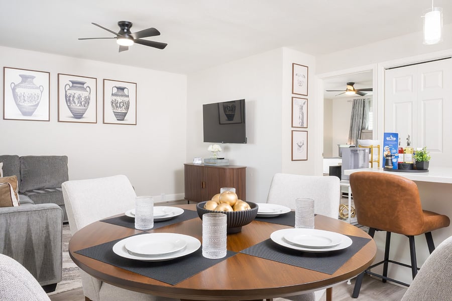 Beautifully set round wooden dining table and modern white upholstered chairs.