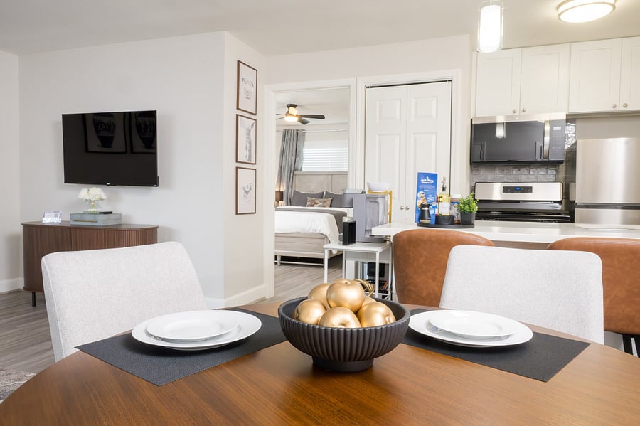 Open-concept home, featuring a stylish wooden dining set, a fully equipped modern kitchen with stainless steel appliances, and a bright living area.