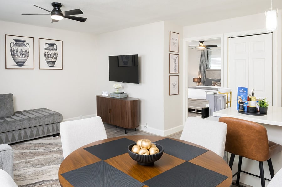 From a stylish wooden dining set to a cozy lounge space with a flat-screen TV, all while offering a view into the master bedroom.